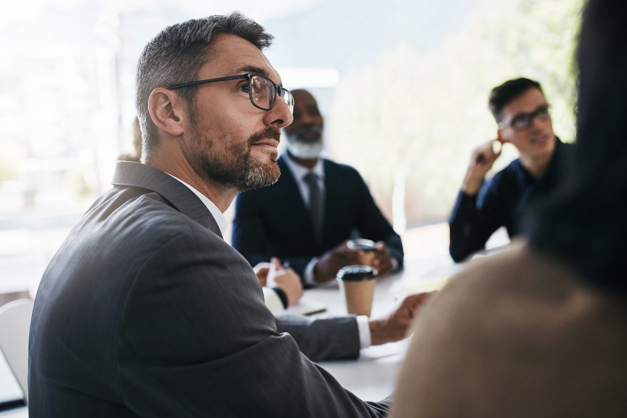 A diverse group of professionals listening attentively in a bright meeting room
